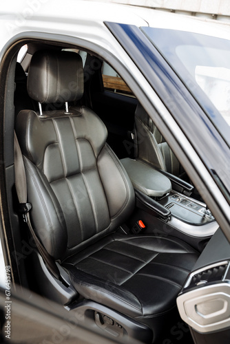 Front view of passenger seat in car, black leather seat upholstery, expensive interior of the vehicle.