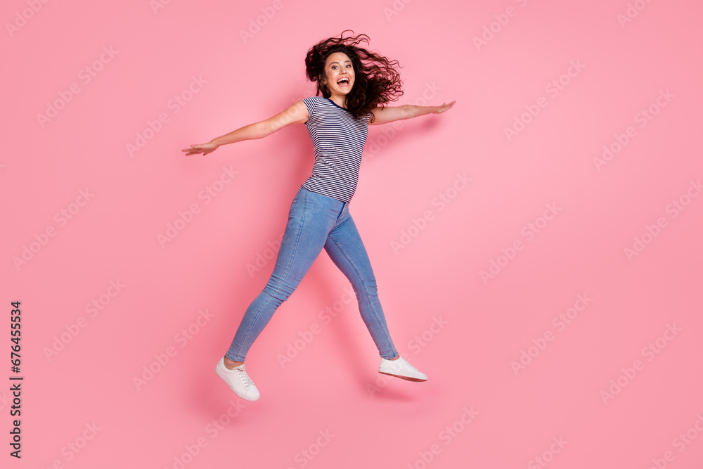 Full body length photo of careless girlfriend having fun flying in air wings arms enjoy active sports isolated over pink color background