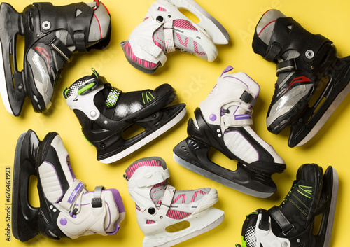 Many ice skates on color background, top view