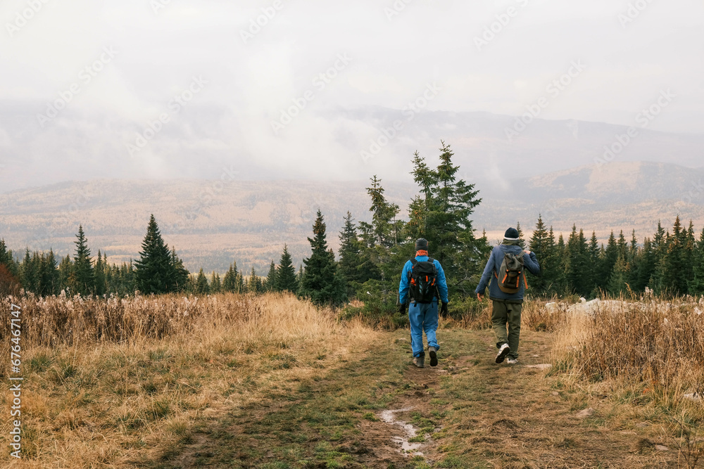 a group of tourists with backpacks is walking through a mountainous area rear view