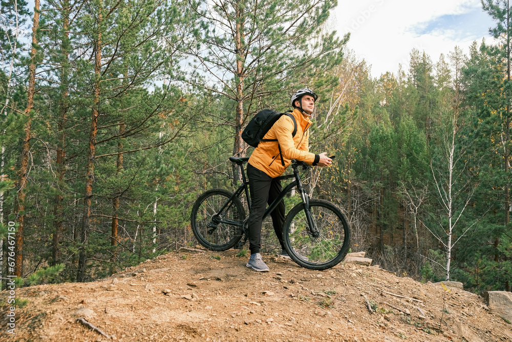 a sporty lifestyle.A man in a protective helmet and equipment stands next to a mountain bike and enjoys nature a sporty lifestyle.A man in a protective helmet and equipment stands next to a mountain bike and enjoys nature
