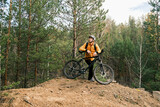 a sporty lifestyle.A man in a protective helmet and equipment stands next to a mountain bike and enjoys nature