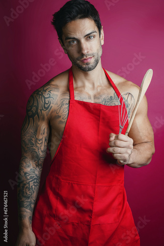 handsome muscular cook holding wooden spoon