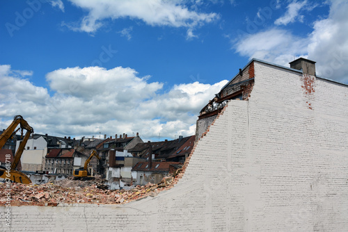 Dismantling the wall of an old building in the historic center of the city. Excavators work from above photo