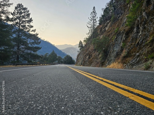 Paved road leading you through the California mountain valley with smoky mountain peaks 