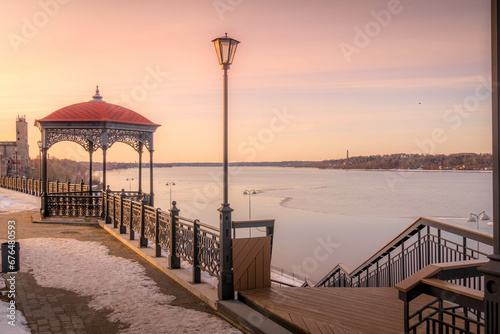 The gazebo and street light at scenic waterfront at Kineshma, Ivanovskaya oblast, Russia, next to the Volga river bank during the winter sunset. photo