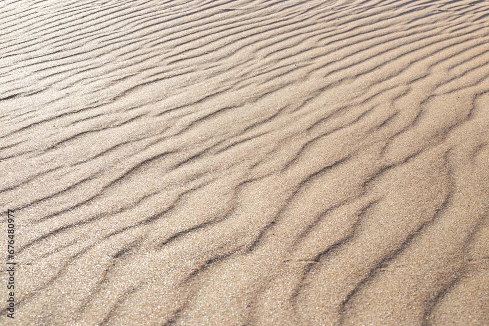 Shiny sand with a wavy pattern, sparkles in the sun, soft focus. Shiny sand with a wavy pattern, sparkles in the sun, soft focus.