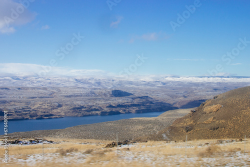 Beautiful landscape with mountains on the horizon covered with snow, a river and dry grass in the foreground
