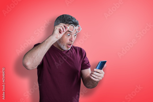 Shocked man while watching in smartphone on yellow background © Aleksej