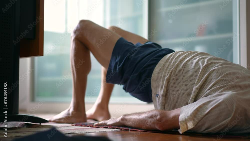 Senior man taking care of his lower back in morning exercise routine to relieve back pain. Elderly caucasian 70s person doing bridge  position, spine health in old age