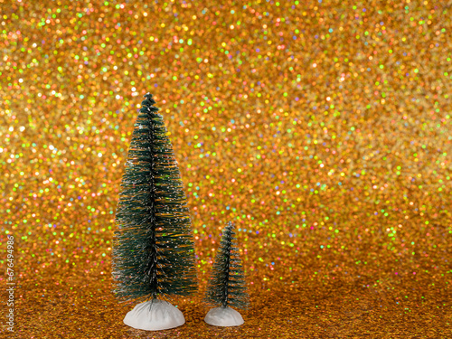 The photo shows a festive scene with decorative artificial Christmas trees set on shiny white snow. The backdrop features a shimmering gold backdrop that adds elegance and magic to the winter wonderla photo
