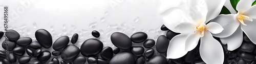 SPA smooth black stones on a white sand and beautiful flowers background. Copy space for text, banner. © serdjo13