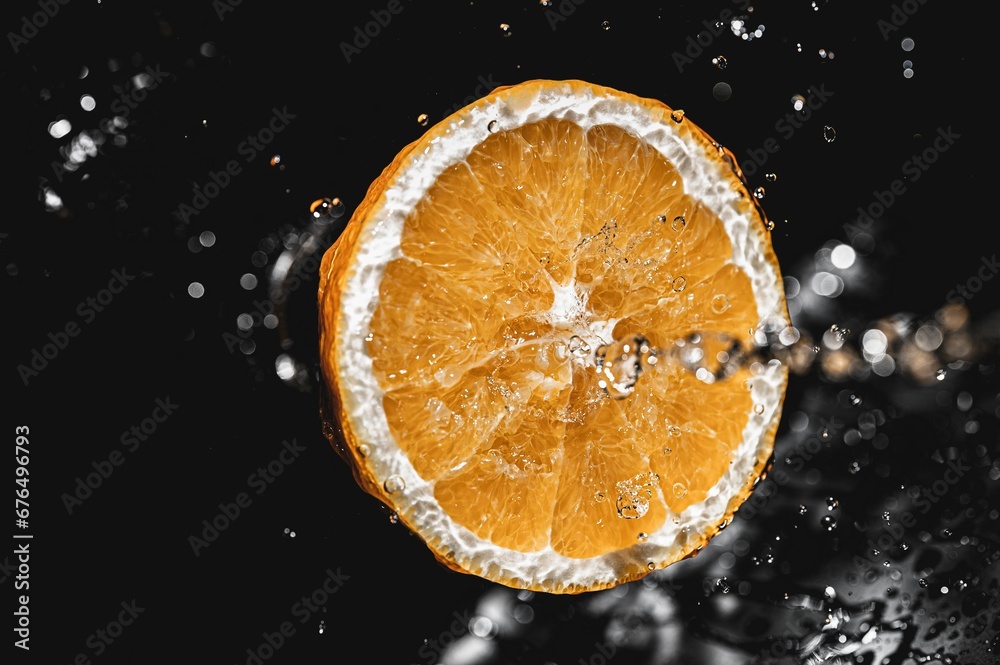 Fresh sliced orange fruit in water splashes isolated on black background Fresh sliced orange fruit in water splashes isolated on black background