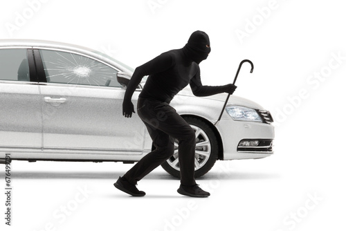 Burglar with balaclava and a crowbar breaking a car window photo