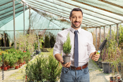 Wallpaper Mural Smiling businessman holding a small tree in a pot and a spade Torontodigital.ca