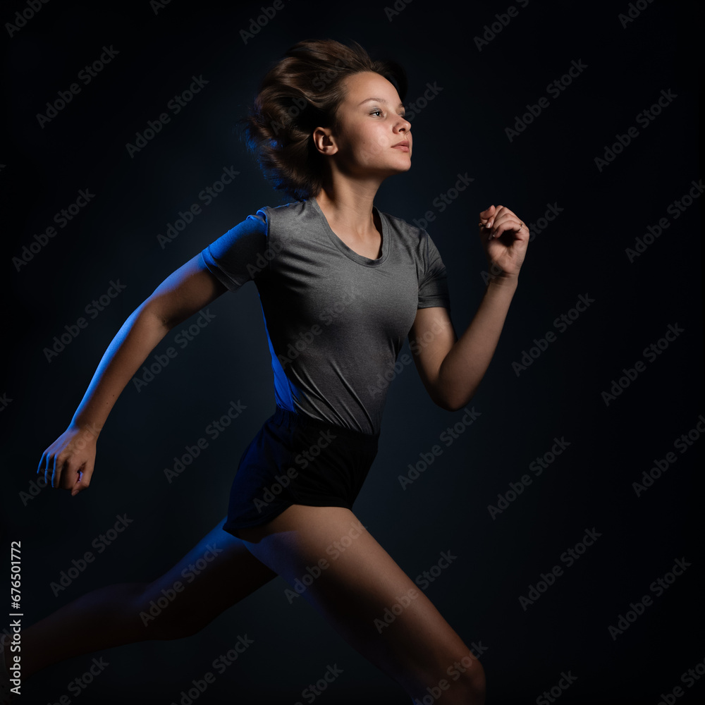 Teen girl athlete running against black background
