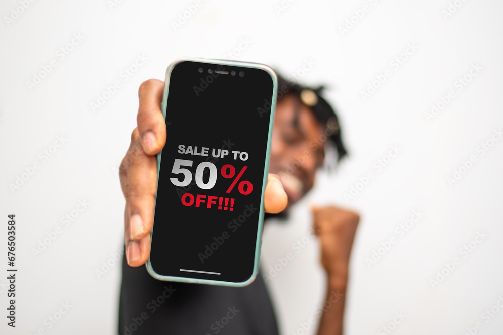 Fototapeta premium Design sale 50% discount. Man hand holding smartphone with discount offer message on the screen, black background sale poster template.