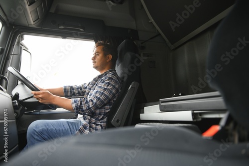 A young Indian male truck driver sits behind the wheel