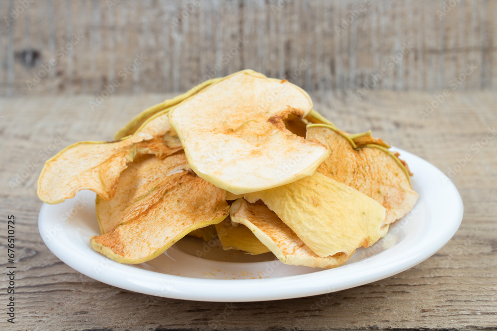 Sliced, dried apples in a plate isolated on wooden background. Homemade organic apple. Sliced, dried apples in a plate isolated on wooden background. Homemade organic apple.