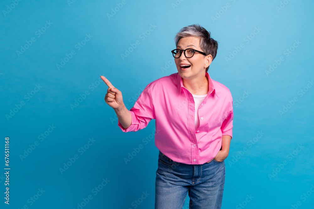 Portrait of impressed funky person wear stylish blouse in eyewear indicating at empty space billboard isolated on blue color background