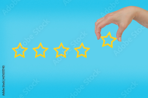 Woman's hand put the stars to complete five stars. Customer satisfaction concept. copy space and blue background. giving a five star rating. Service rating, satisfaction concept. photo