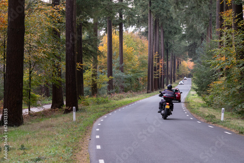 Provincial road with a motorcyclist and cars in the fall.