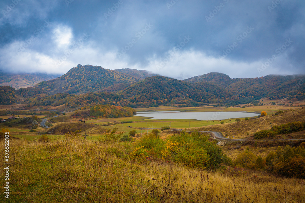 Fototapeta premium Thick clouds slide down from the mountains and are swirled by the wind. Autumn landscape in the mountains near the lake.