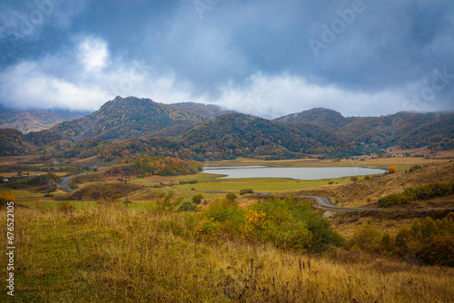 Thick clouds slide down from the mountains and are swirled by the wind. Autumn landscape in the mountains near the lake.