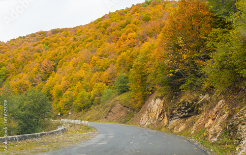 Winding road to the mountains. Sunny autumn in the mountains covered with bright colorful trees.