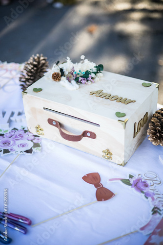 Mariage boite, urne à dons posée sur une table au-dessus d'un napperon blanc et entourée de décoration photo