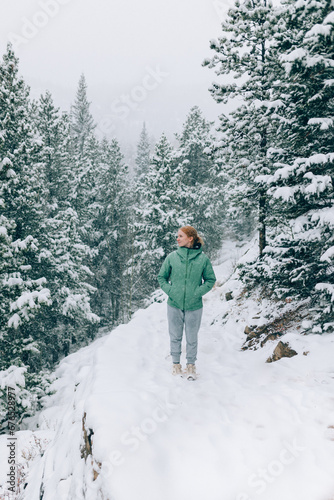 Female hiker walking through the snow woods and mountains