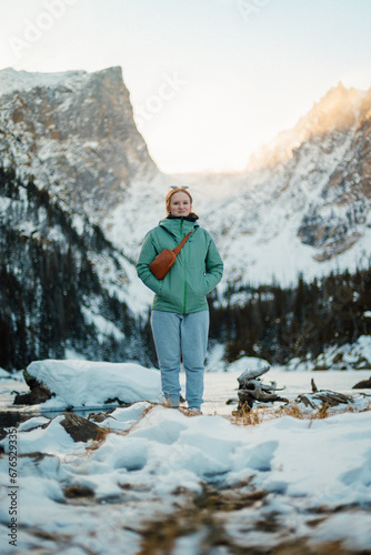 Female Hiker enjoying stunning views of the mountains beside a frozen lake 
