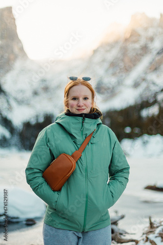 Female Hiker enjoying stunning views of the mountains beside a frozen lake 