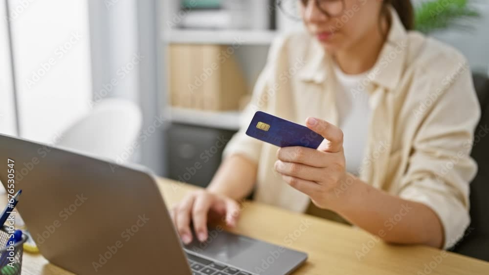 Smiling young hispanic woman, a beautiful business worker, confidently navigating online finance using her credit card and laptop at the office. Smiling young hispanic woman, a beautiful business worker, confidently navigating online finance using her credit card and laptop at the office.