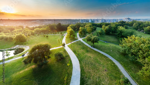 top view aerial photo from flying drone of a city park with walking path and green zone trees in evening time urban park with meadow trees and paths photo
