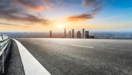 panoramic city skyline and buildings with empty asphalt road at sunset photo