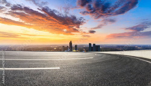 round asphalt road and city skyline with colorful sky clouds at sunset