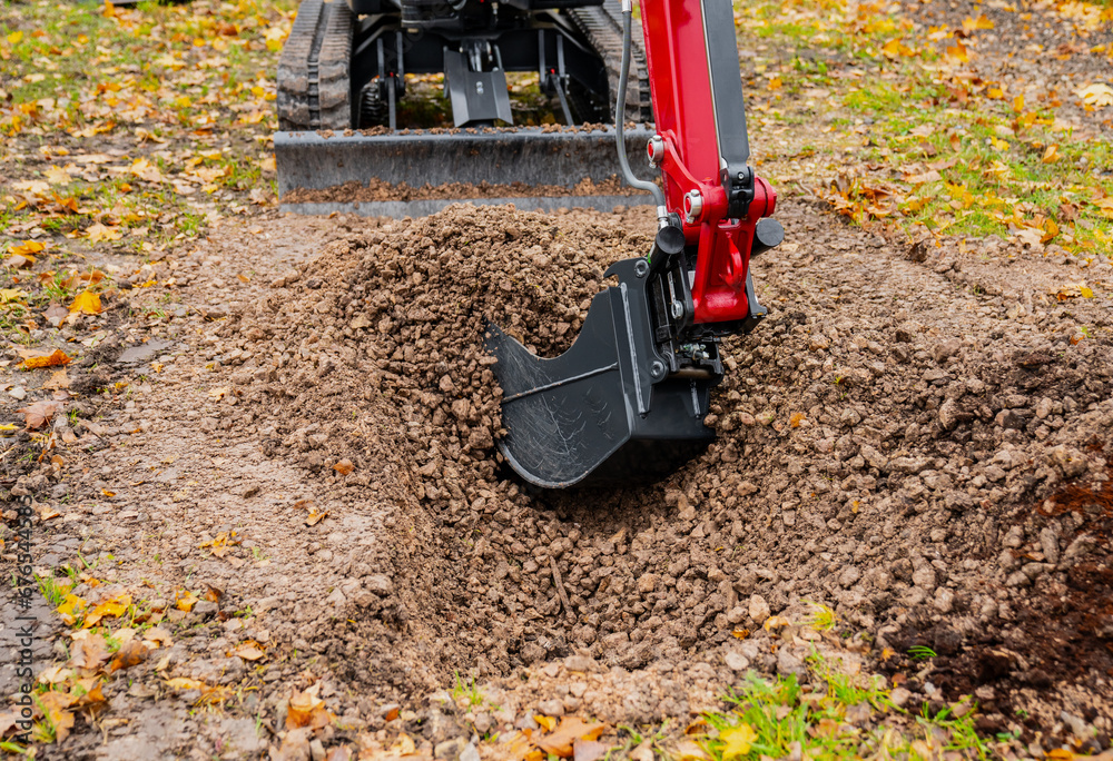 Micro ditching bucket on mini excavator working on earthmoving project on the ground Micro ditching bucket on mini excavator working on earthmoving project on the ground