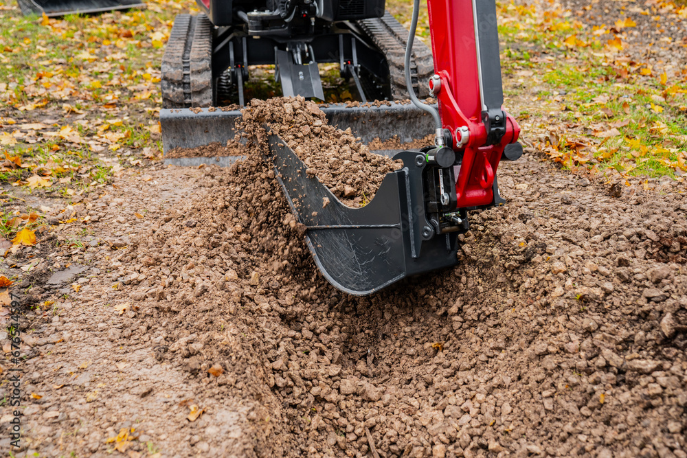Micro ditching bucket on mini excavator working on earthmoving project on the ground Micro ditching bucket on mini excavator working on earthmoving project on the ground