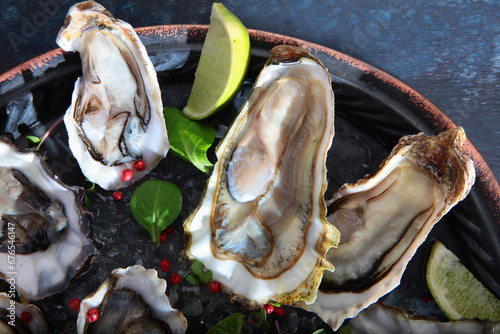 Fresh oysters with lime on round plate. Several varieties of oysters. Oyster in half shell. Flat lay. Top view. Copy space.