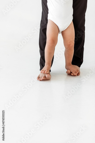 child standing on dad's feet. dad and baby feet.