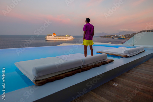 Man relaxes on the sunbed during sunset time at Mykonos, Greece