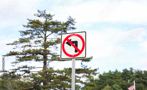 No Turn sign stands tall, a symbol of traffic rules and order, against a backdrop of urban buildings and a cloudy sky