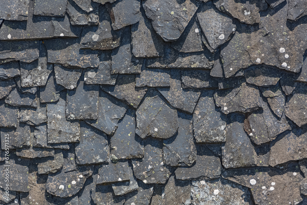 Detailed view of wall texture randomly lined with slate panels, typical and traditional shale stone material, used as external waterproof cladding in construction Detailed view of wall texture randomly lined with slate panels, typical and traditional shale stone material, used as external waterproof cladding in construction