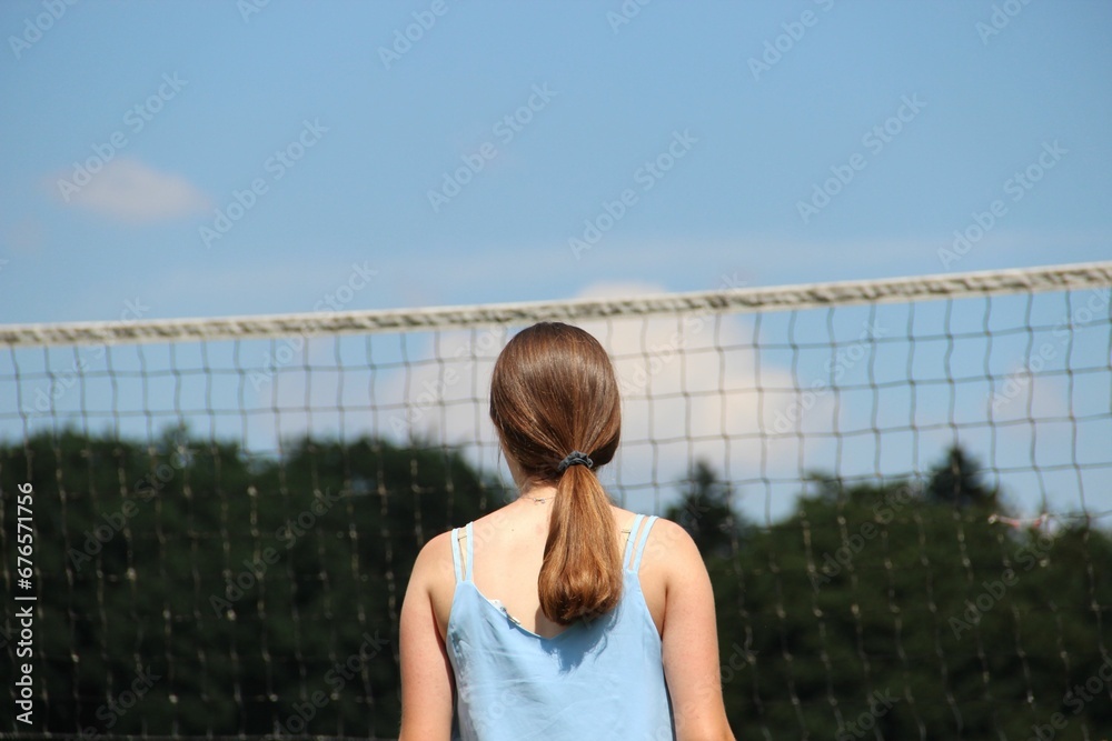 Woman standing near a volleyball net in a park on a sunny day Woman standing near a volleyball net in a park on a sunny day
