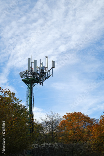 Nature vs. Technology: Harmony in Contrast. communications antenna among autumn trees in vertical format.