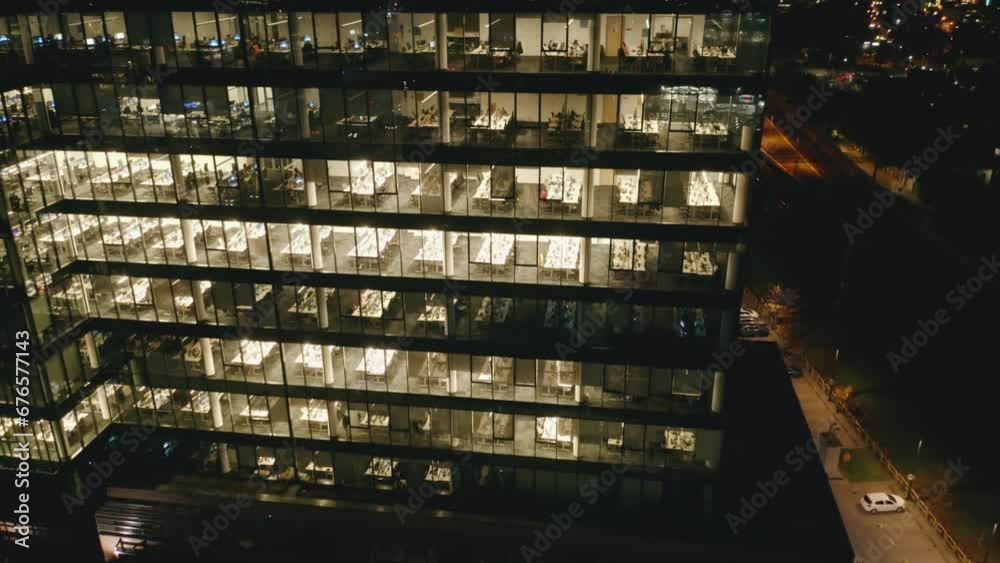 Aerial view of an office building in the evening with illuminated workspaces