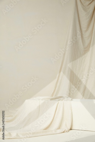 Vertical shot of a white flowing cloth in a white room