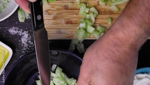 Close up of the Chef's hands preparing traditional Bulgarian salad Snejanka consisting of diced cucumbers, strained greek yogurt, minced garlic cloves olive oil and salt. photo