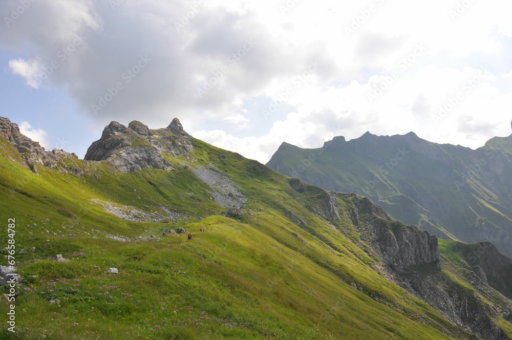 Mesmerizing landscape of a steep slope covered by grass with mountains in the background Mesmerizing landscape of a steep slope covered by grass with mountains in the background